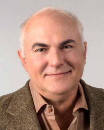 A man with white hair and a brown jacket.